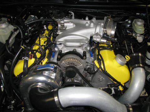 2003 Mercury Marauder - Engine bay a polished supercharger and bright yellow valve covers, with visible "SUPERMOTORS" text on a pipe.