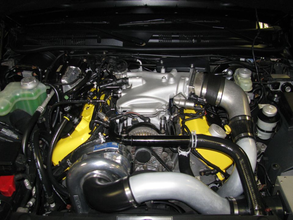 Engine bay with silver intake manifold, yellow valve covers, and a large turbocharger