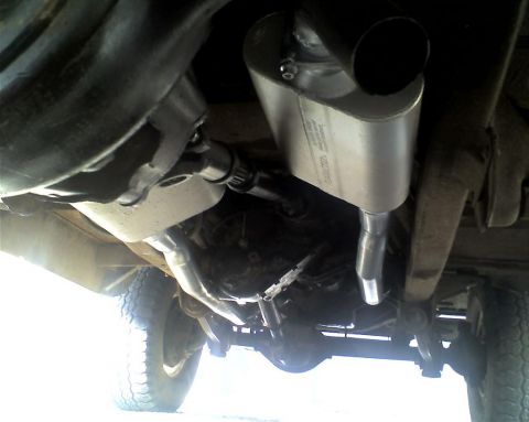 1968 Ford Bronco - A view from underneath a vehicle shows the exhaust system and drivetrain components, including mufflers and drive shafts.