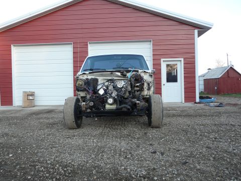 1994 Ford F-150 - Head-on view of a white pickup cab and chassis on gravel in front of a red steel shop, stripped of hood, fenders, grille and front bumper s…
