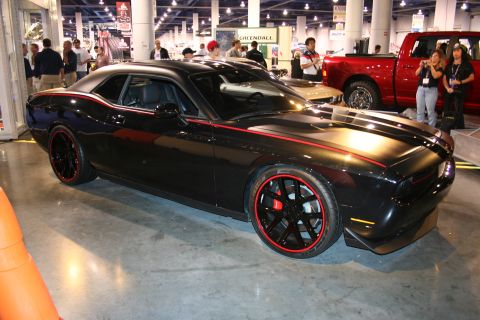 1998 Ford Crown Victoria - A black coupe with red racing stripes and custom wheels is displayed indoors, with other vehicles and people in the background.