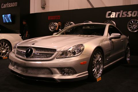 1998 Ford Crown Victoria - A silver Mercedes-Benz coupe is displayed with custom wheels and Carlsson branding on the wall behind it.