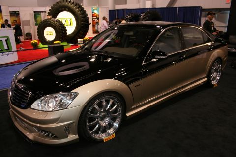 1998 Ford Crown Victoria - A customized Mercedes-Benz S-Class sedan with a black and tan paint scheme is shown at an indoor event.