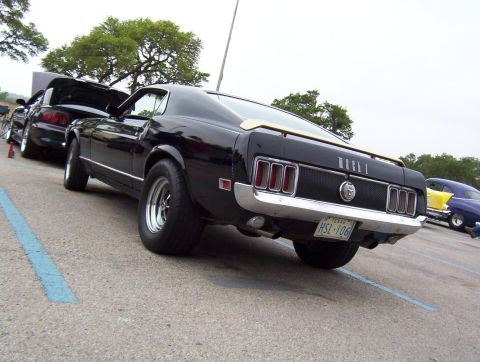 1970 Ford Mustang - A black 1970 Ford Mustang Mach 1 is parked in a lot with other vehicles.