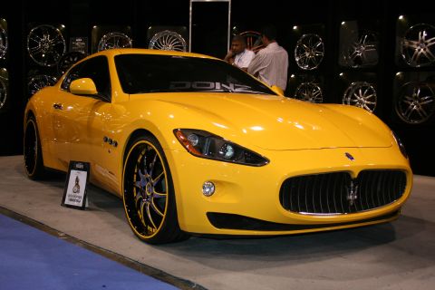 1998 Ford Crown Victoria - A bright yellow Maserati GranTurismo is displayed with custom rims and a banner across the windshield.