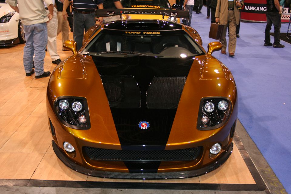 Gold and black sports car with custom headlights and a large rear spoiler