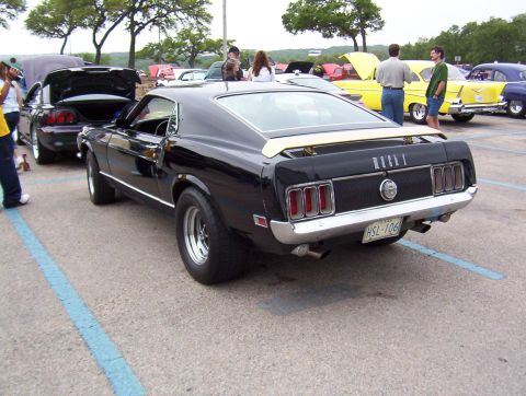 1970 Ford Mustang - Rear view of a black 1970 Ford Mustang Mach 1, a yellow stripe on the trunk lid and a license plate reading HSL 106.