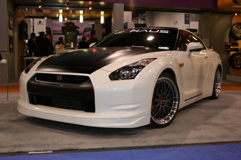 1998 Ford Crown Victoria - A white Nissan GT-R with a black hood and custom wheels is displayed indoors.