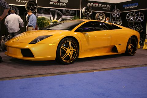 1998 Ford Crown Victoria - A yellow Lamborghini sports car is displayed with custom wheels at an auto show.