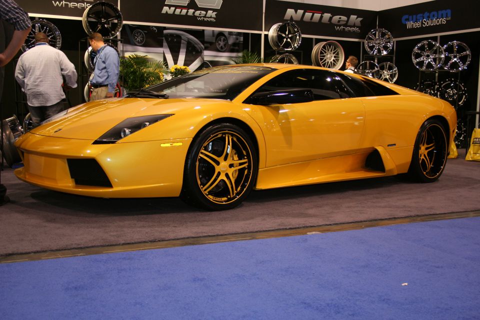 Yellow Lamborghini sports car with custom black and gold wheels on display
