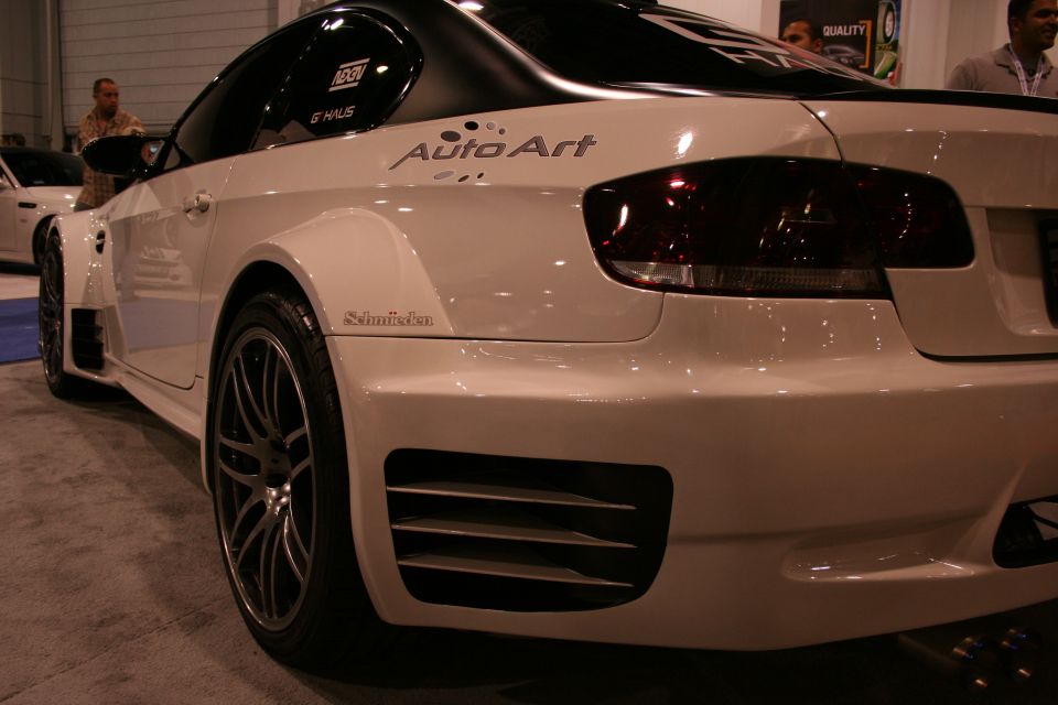 Modified white coupe with wide fenders and custom body kit, showing 'Auto Art' and 'Schmiedmann' decals