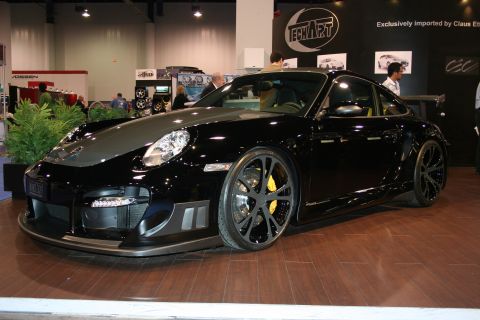 1998 Ford Crown Victoria - A black Porsche 911 with a custom body kit and distinctive wheels is displayed indoors.