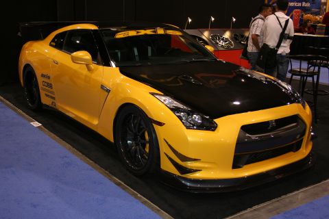 Yellow Nissan GT-R with black hood and spoiler, covered in decals