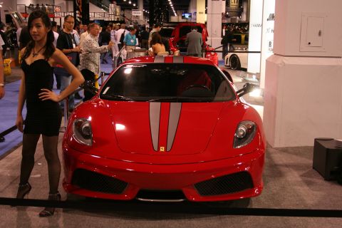 Red sports car with silver racing stripes on the hood, front view