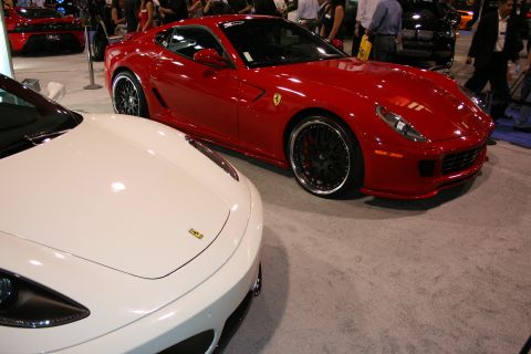 Red Ferrari next to a white Ferrari at a car show