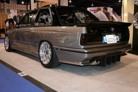 Modified BMW E30 M3 with custom body kit and large spoiler, seen from the rear