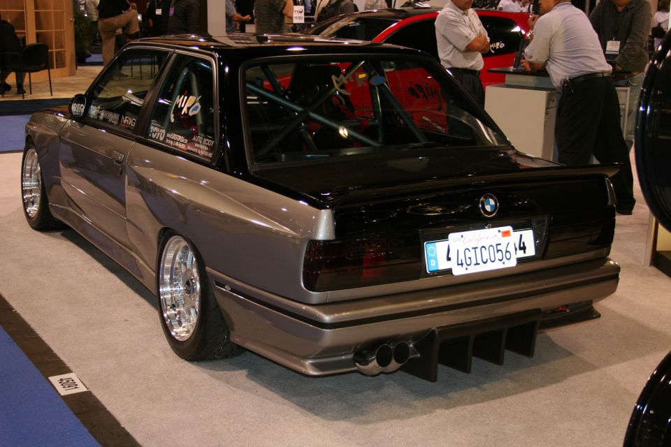 Modified BMW M3 with widebody kit, custom exhaust, and roll cage, viewed from the rear