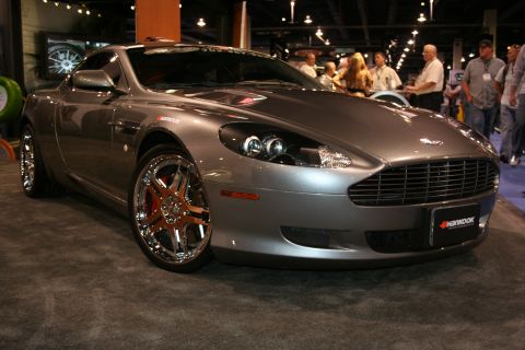Gray Aston Martin DB9 with chrome rims and red brake calipers, parked indoors