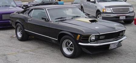 1970 Ford Mustang - A black 1970 Ford Mustang is parked outdoors with other vehicles nearby.
