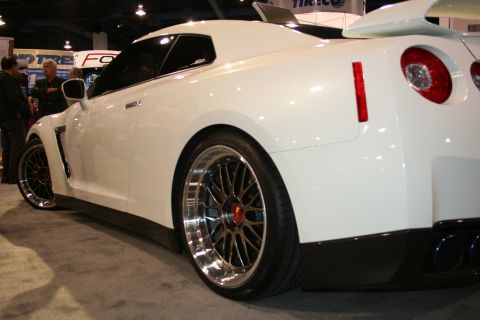 White sports car with custom wheels, rear spoiler, and dual exhaust pipes
