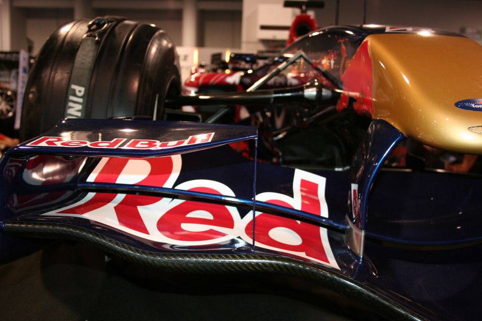 Red Bull F1 car front wing with "Red Bull" logo, carbon fiber details, and gold nose cone