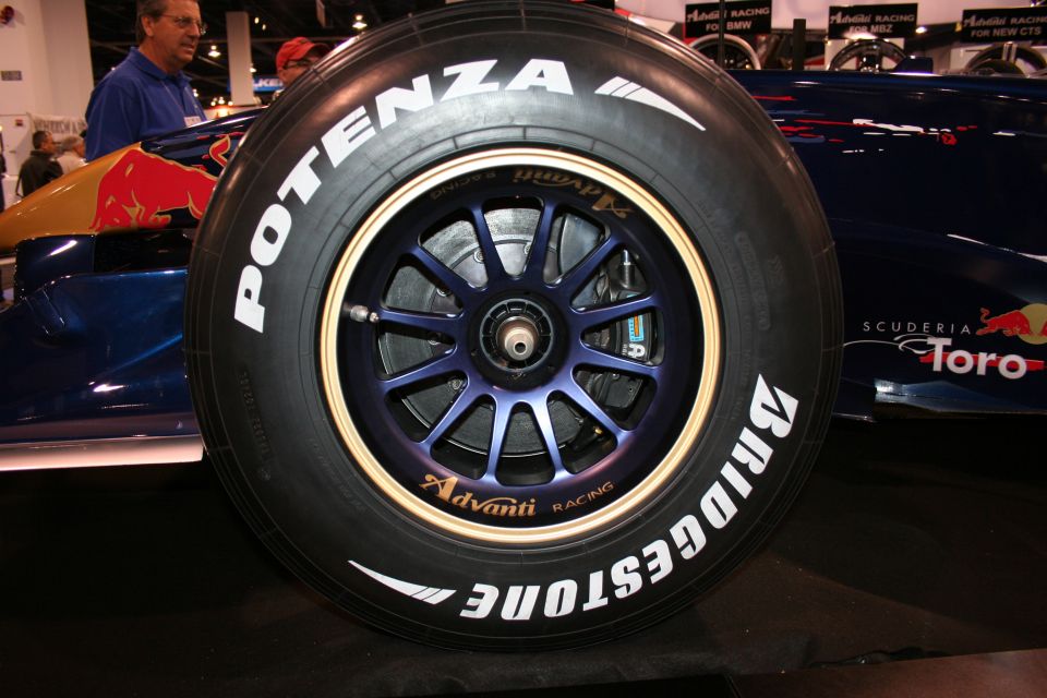 Close-up of a racing tire with Bridgestone and Potenza branding, showing a multi-spoke wheel