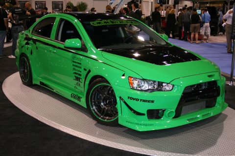Green Mitsubishi Lancer Evolution with black hood and roof, custom decals, and aftermarket wheels
