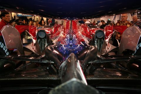 Front view of a red and blue race car with exposed engine components and exhaust pipes