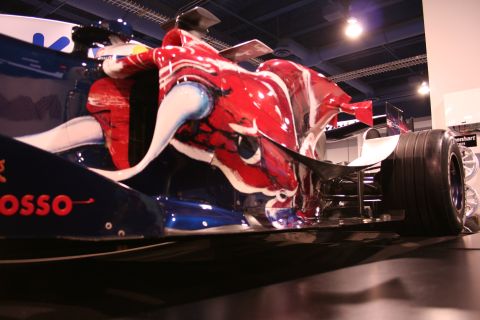 Red and blue Formula 1 race car with dragon-like artwork on the side, low angle view