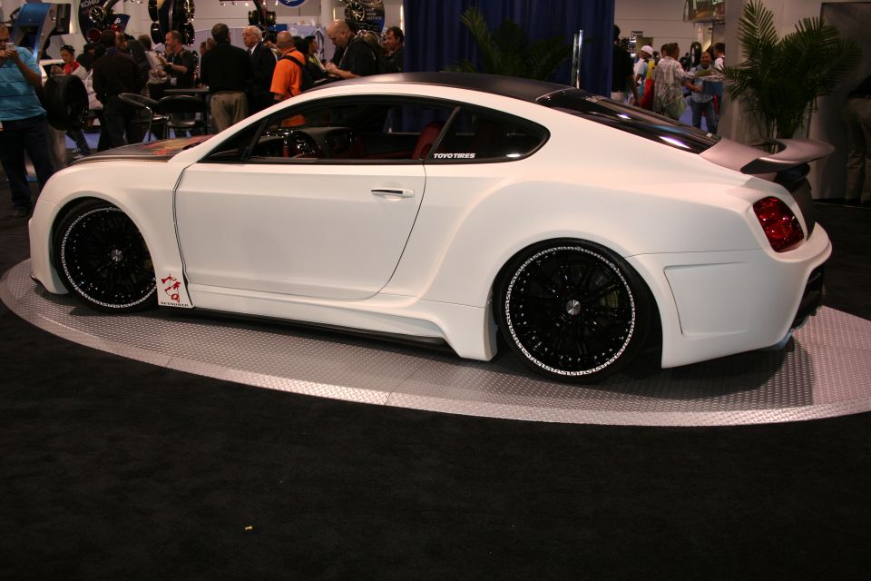 White custom coupe with black rims and wide body kit, parked indoors