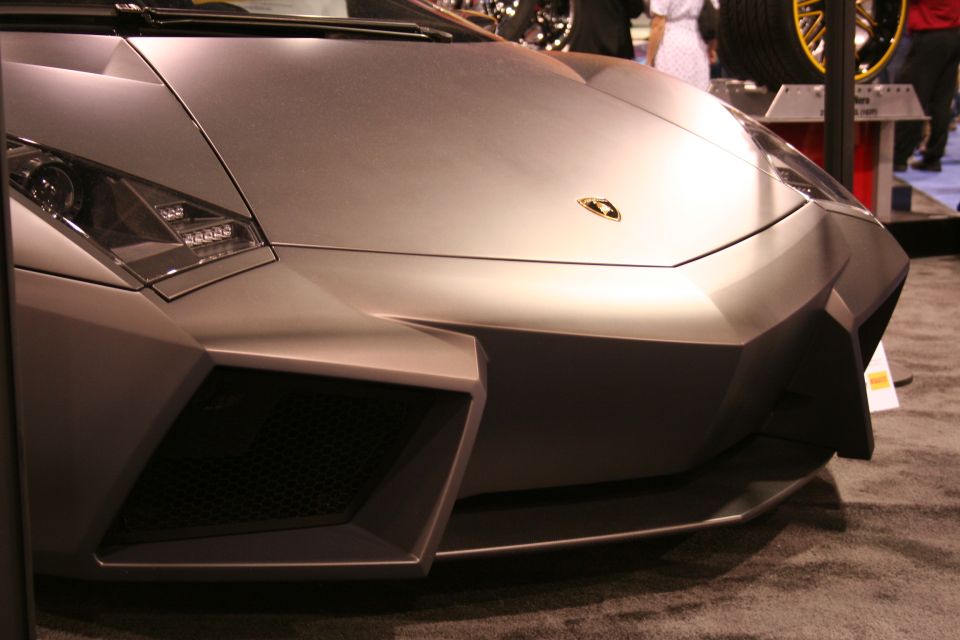 Matte silver Lamborghini Aventador front end, angled view. Gold emblem visible