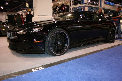 Black Aston Martin DBS coupe on display at an indoor auto show