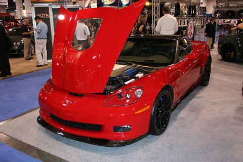 Red Chevrolet Corvette with open hood at an indoor auto show
