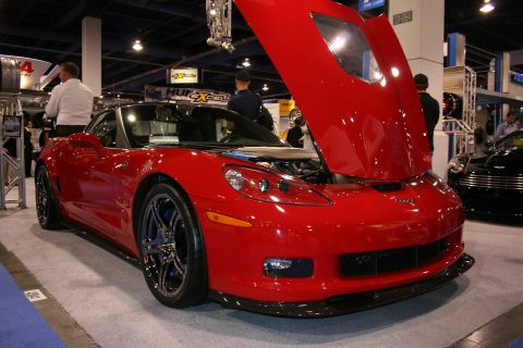 Red Chevrolet Corvette with raised hood at an auto show