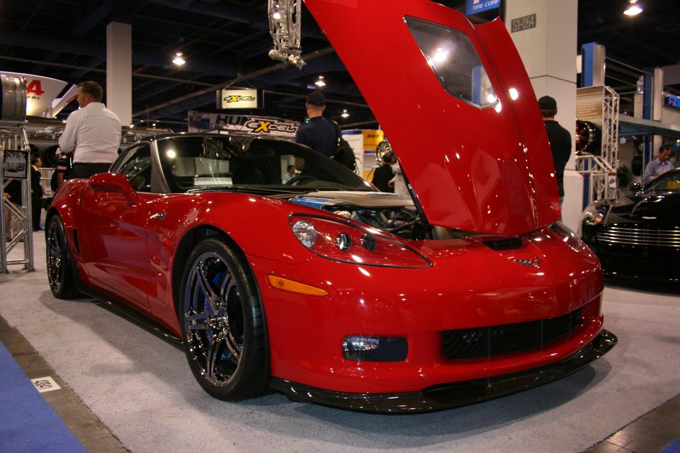 Red Chevrolet Corvette with raised hood at an auto show