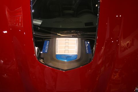 Engine cover under the hood of a red Corvette ZR1 with blue coil covers