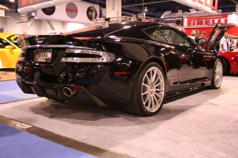 Rear of a black Aston Martin DBS coupe at an indoor auto show