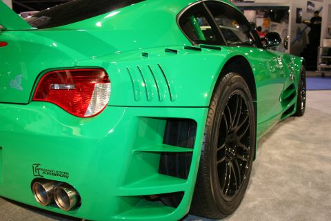 Green sports car rear quarter at an auto show with twin exhaust tips