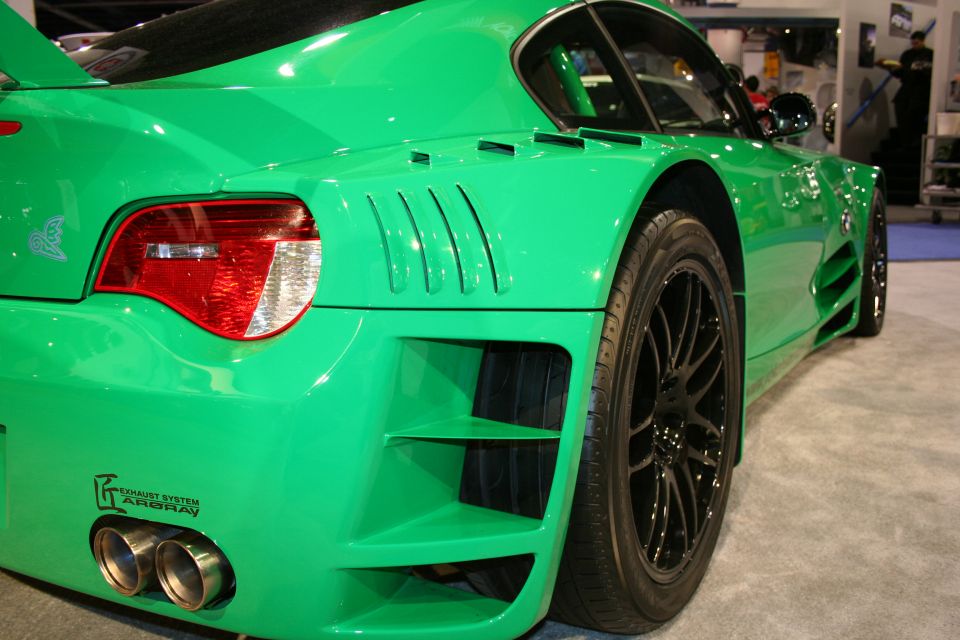 Green sports car rear quarter at an auto show with twin exhaust tips