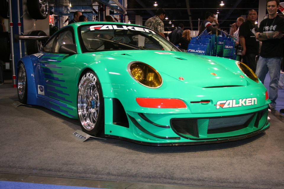Teal Falken Porsche 911 GT3 race car front view at an auto show