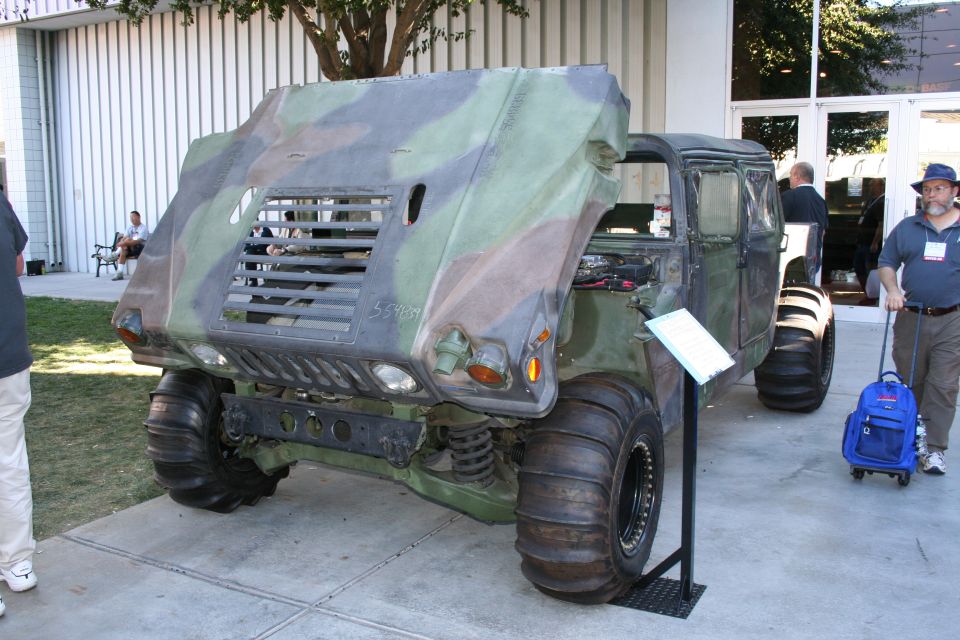 Camouflaged military off-road vehicle parked outdoors at a display