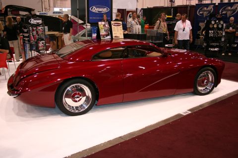 Dark red custom streamliner car side profile at a trade show