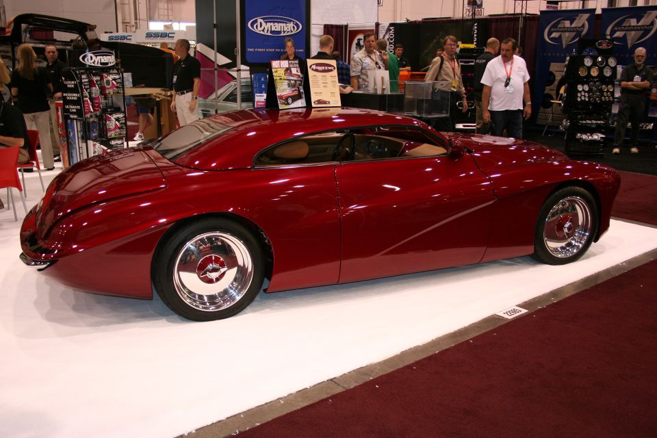Dark red custom streamliner car side profile at a trade show