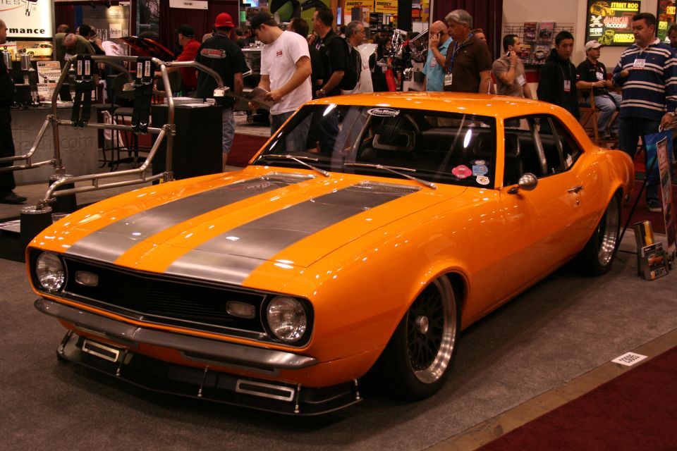 Orange 1967 Camaro with silver racing stripes, front 3/4 view