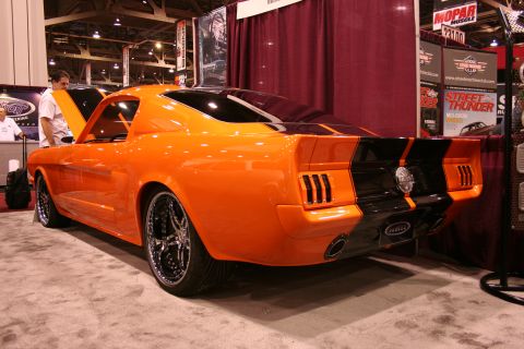 Orange custom classic car with black stripes, rear view. It has triple vertical vents on each side of the trun