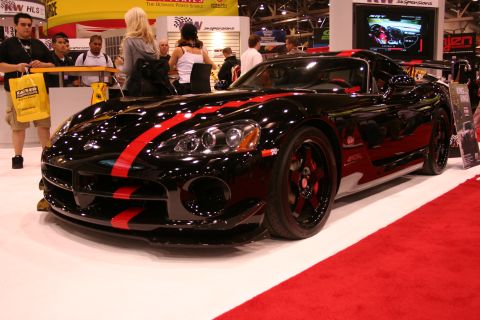 Black Dodge Viper with red stripe at a trade show booth