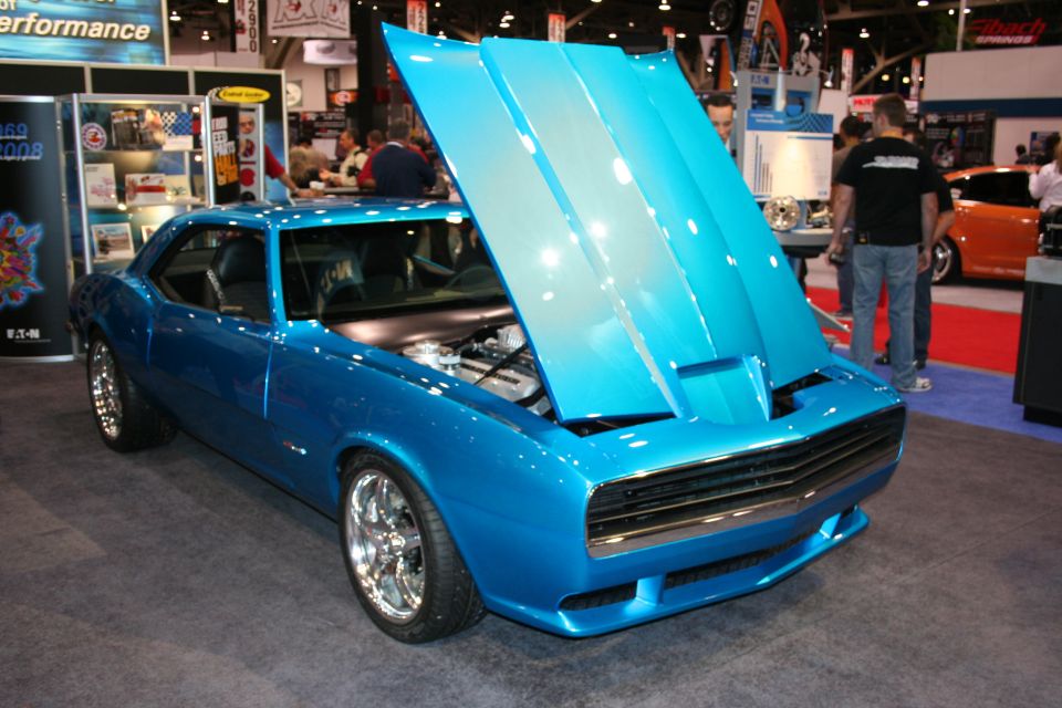Blue first-gen Camaro custom with open hood at trade show