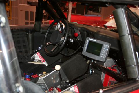 Race car interior with steering wheel, roll cage, and dash-mounted electronic display