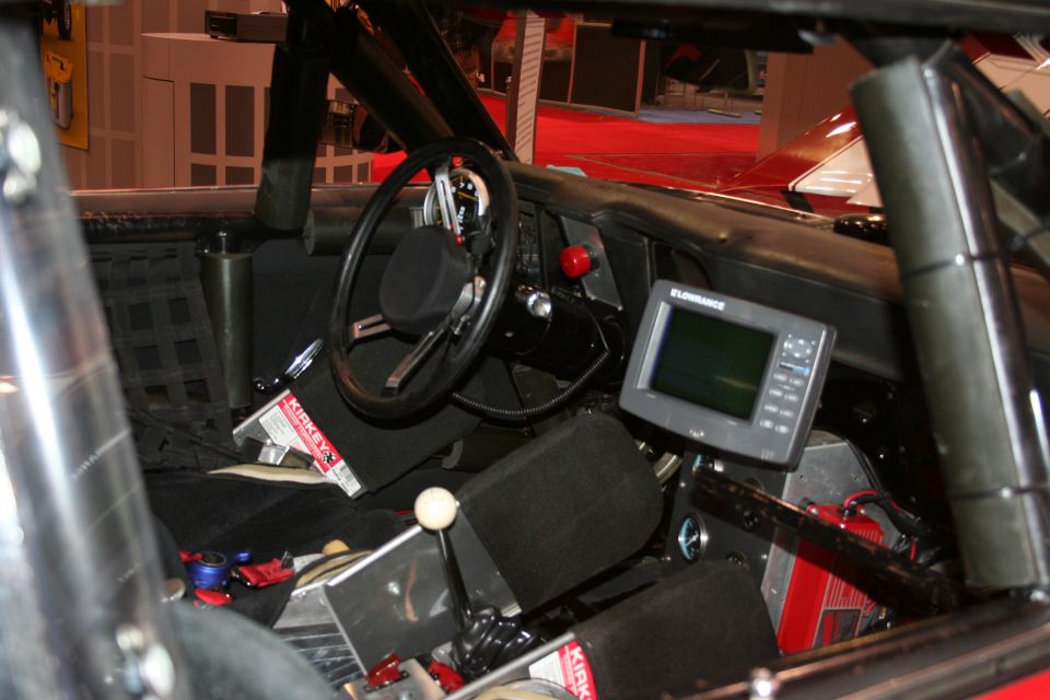 Race car interior with steering wheel, roll cage, and dash-mounted electronic display
