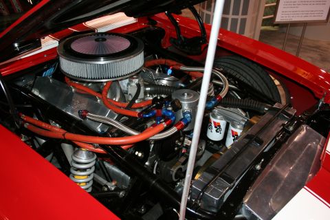 Engine bay of a red show car with chrome air cleaner and braided lines